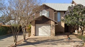 Une maison à deux étages avec un garage, un toit en pente et un petit porche.