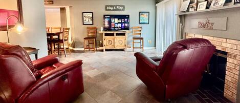 A living room with two leather recliners, a fireplace, and a television in the background.