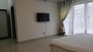 Habitación de hotel con cama, televisión en la pared y ventana con cortinas.