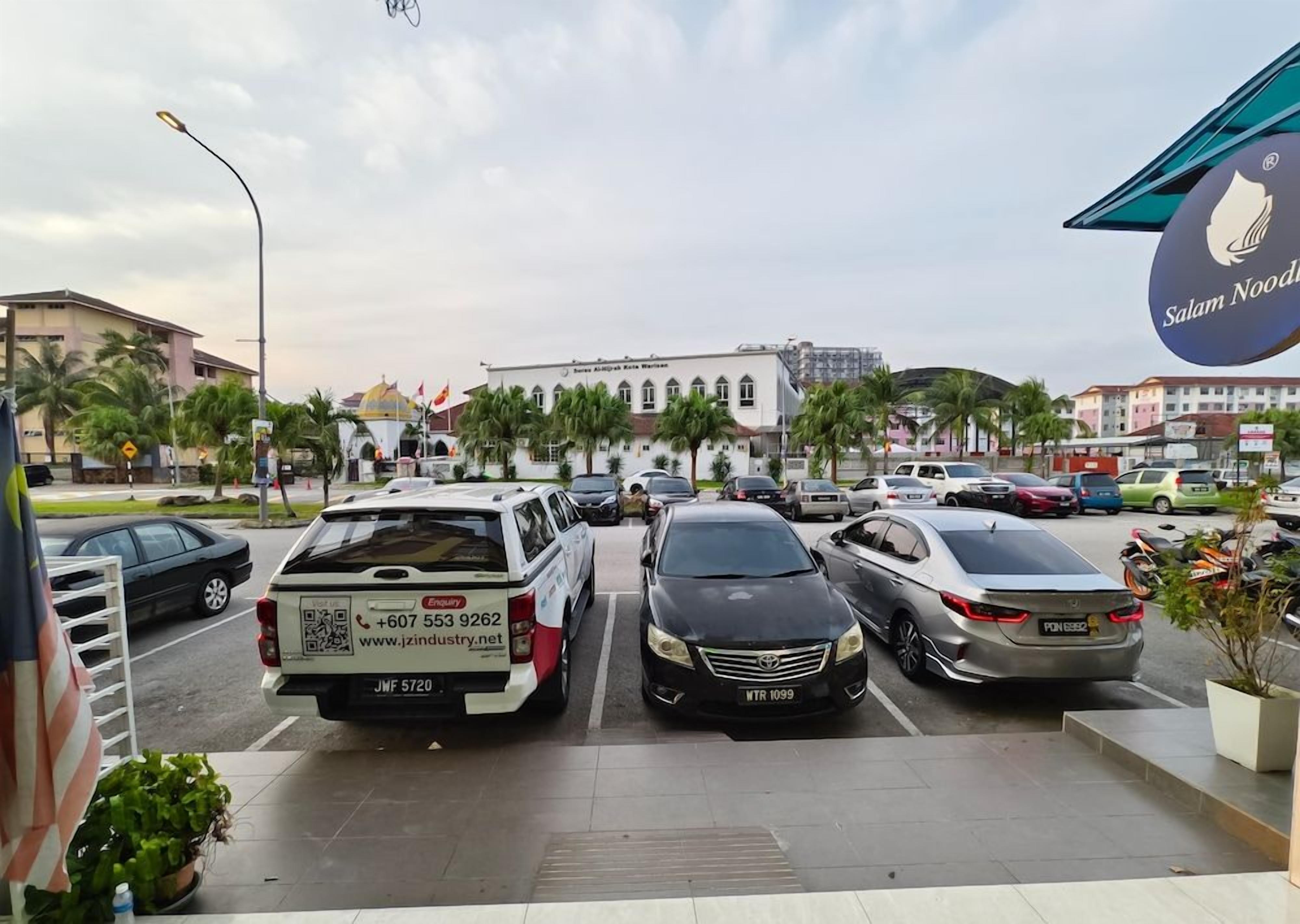 A parking lot with several cars, a white van with a QR code, and a building with a dome in the background.