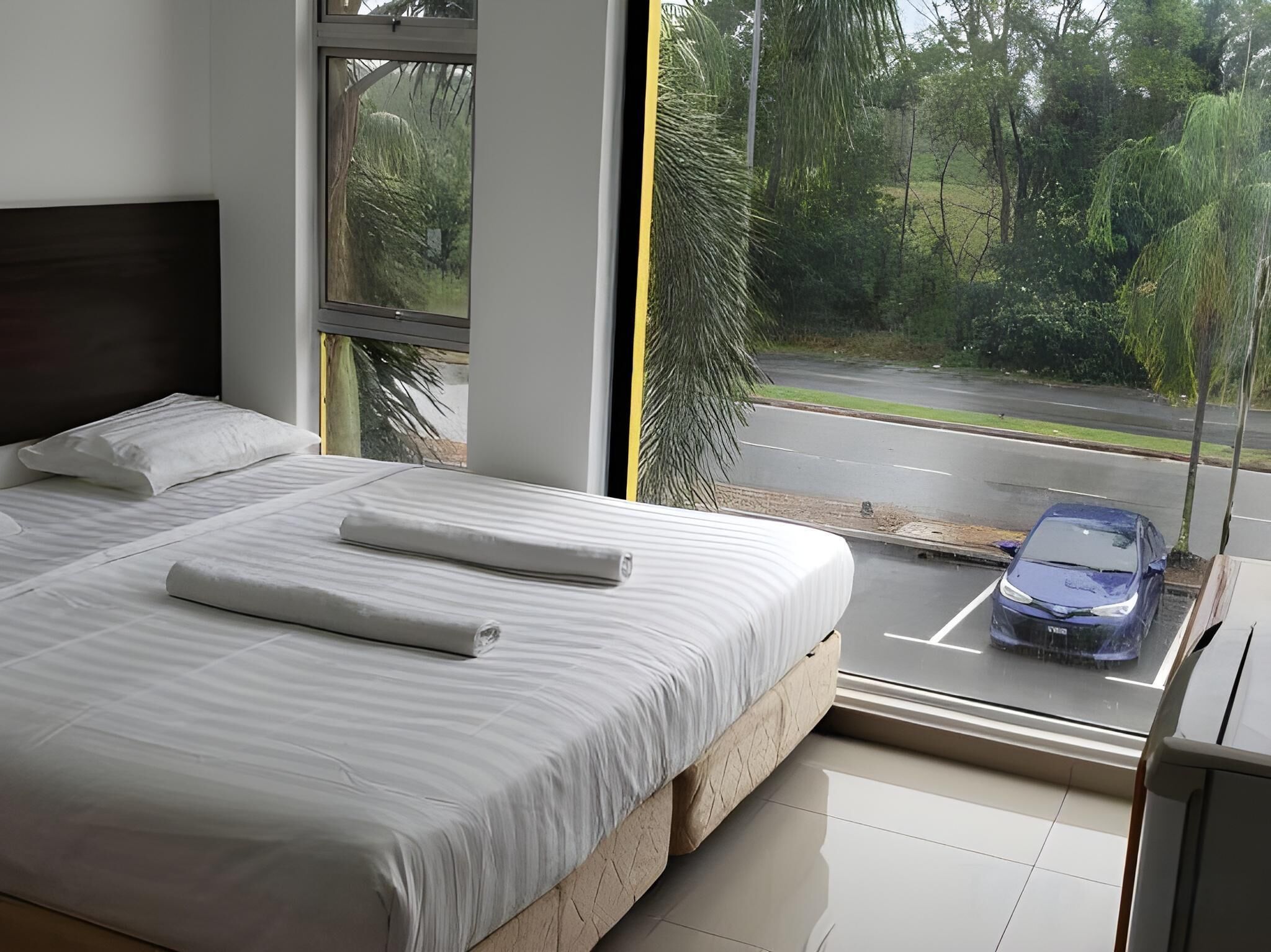 A bedroom with a large bed, a window, and a view of a street.