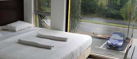 A bedroom with a large bed, a window, and a view of a street.