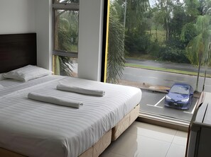 A bedroom with a large bed, a window, and a view of a street. - S Rose Hotel (Sepang)