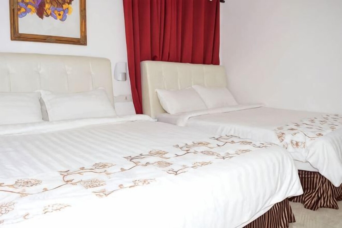 Una habitación de hotel con dos camas, una cortina roja y un cuadro en la pared.