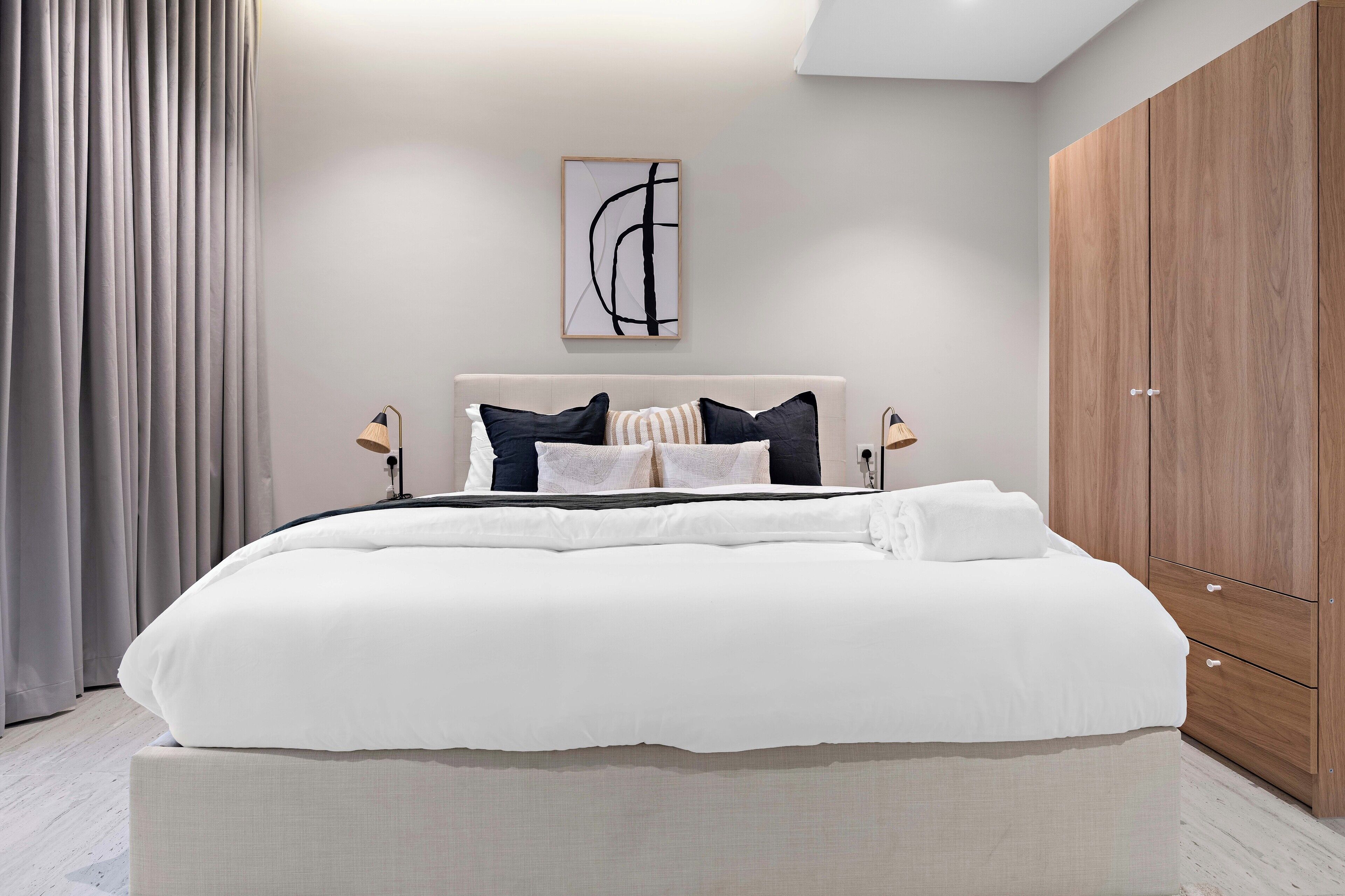Un dormitorio moderno con una cama grande, un armario de madera y una obra de arte minimalista en la pared.