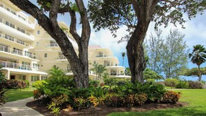 Un hotel con un jardín exuberante, árboles grandes y un césped cuidado.