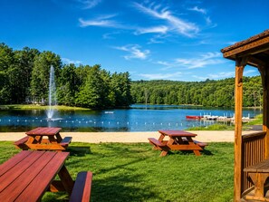 Picnicområde ved søen med to træborde og en pavillon.