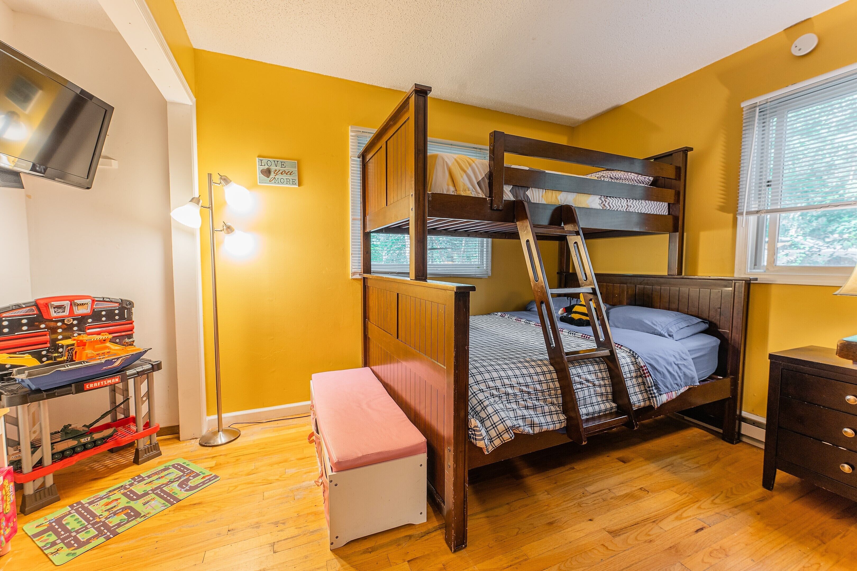 A bunk bed room with a desk and a TV.
