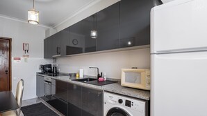Een moderne keuken met een wasmachine, magnetron en spoelbak.