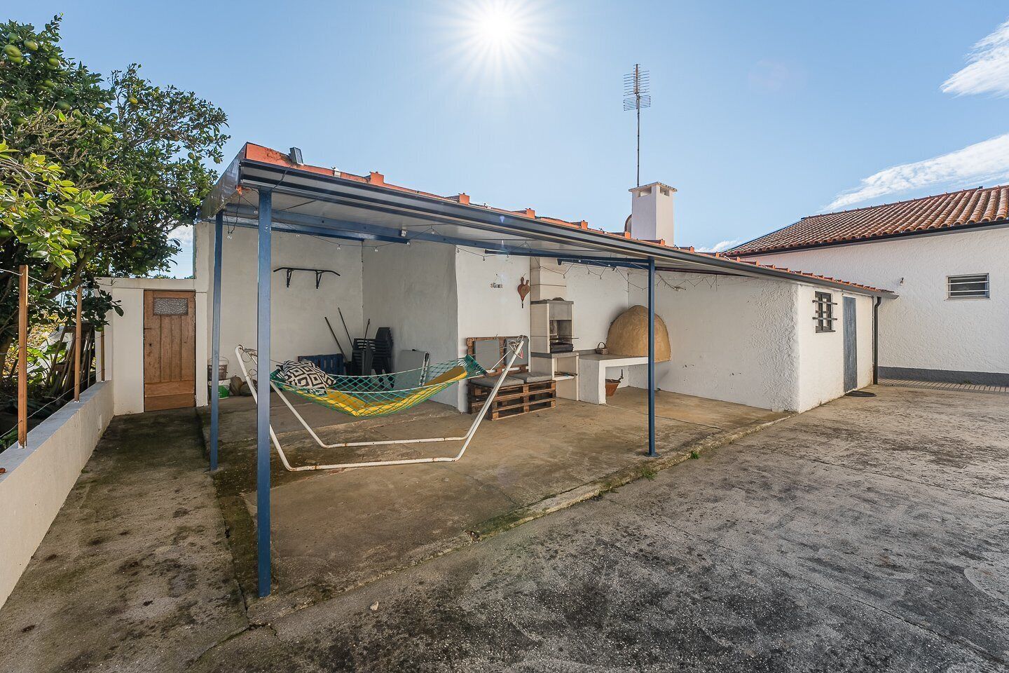 Un espace extérieur abrité comprenant un hamac, un barbecue et une petite terrasse.