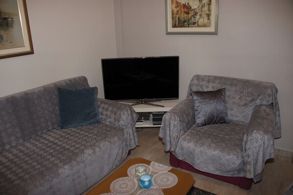 A living room with two patterned sofas, a flat-screen TV, and a coffee table with a candle.