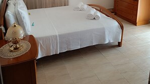 A neatly arranged bedroom with a bed, a wooden wardrobe, a dresser, a mirror, and a hanging lamp. - Panos House - Warm and cozy retreat (Trikala)