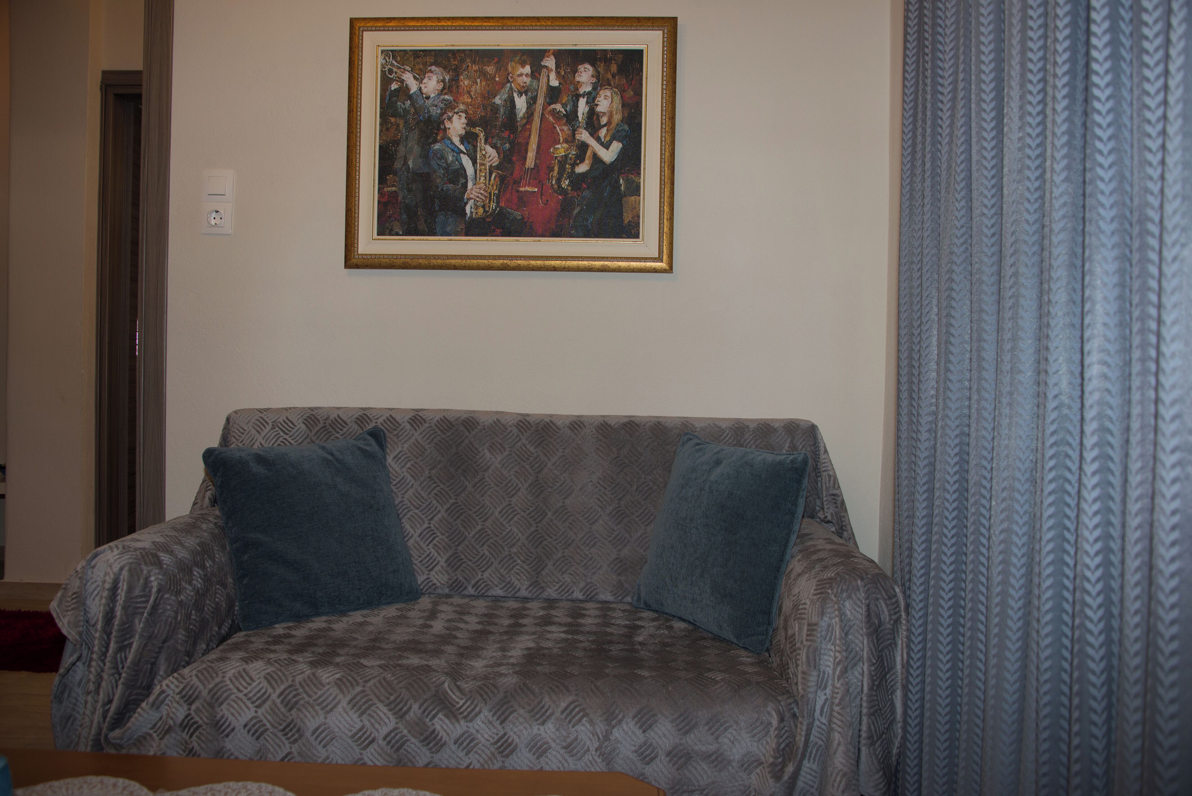 Un soggiorno con un divano decorato, un quadro incorniciato e una tenda fantasia.