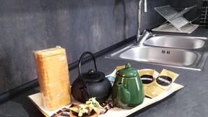 A kitchen counter with a bread loaf, a black kettle, a green teapot, and coffee pods. - Panos House - Warm and cozy retreat (Trikala)
