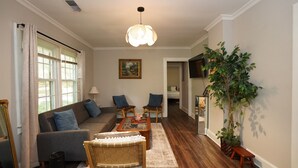 A living room with a sofa, two chairs, a coffee table, a lamp, and a large plant. - Pine Haven - Large Group - Baby & Pet friendly (Birmingham)