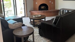 Una sala de estar con chimenea, un sofá, una mesa de centro y un televisor montado en la pared.