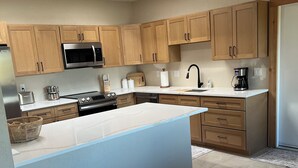 Una cocina moderna con armarios de madera, un microondas de acero inoxidable, un lavamanos y una cafetera.
