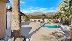 Zona de piscinas con varias albercas, palmeras y montañas al fondo.