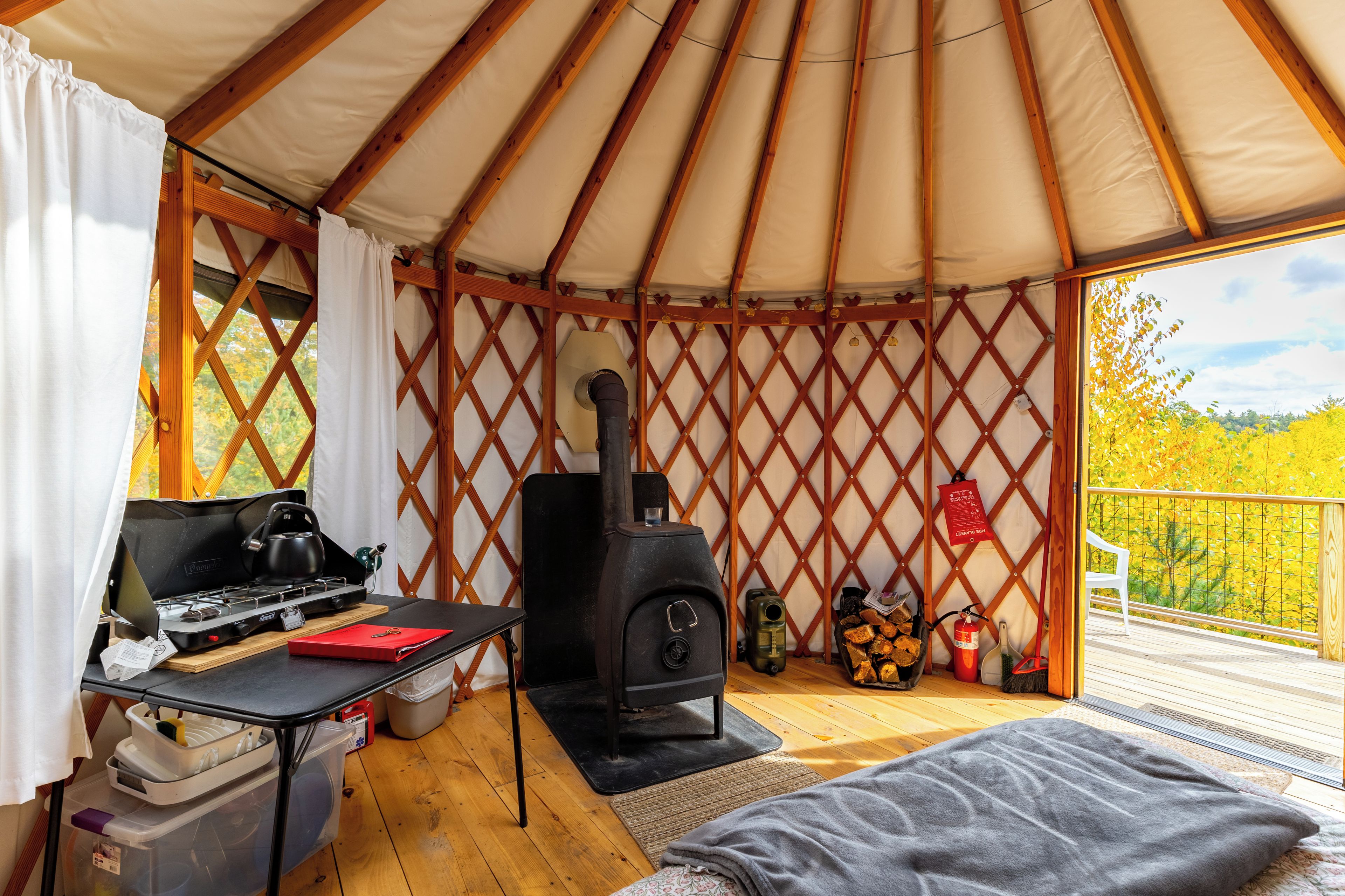 A cozy interior of a tent with a table, a portable stove, and a sleeping area.