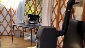Una carpa con una parrilla negra, una mesa con una computadora portátil y una silla.