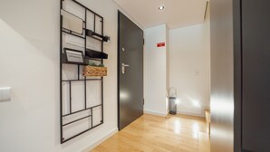 Ein Flur mit Holzboden, einem Wandbild mit schwarzem Rahmen, einer geschlossenen Tür und einem roten Schild an der Wand.