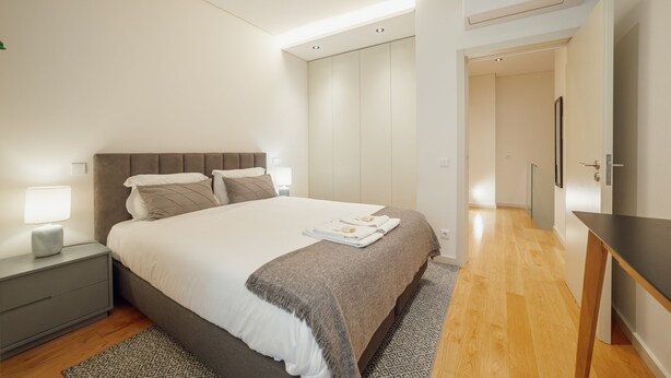 Ein modernes Schlafzimmer mit einem großen Bett, Nachttischen, einem Schreibtisch und einem Kleiderschrank.
