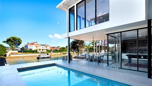 A modern house with a swimming pool, outdoor furniture, and a view of the water. - Luxico Bluewater Oasis (Heated Pool) (Broadbeach Waters)