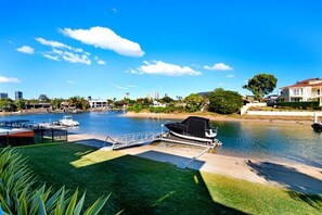 A waterfront property with a dock, a boat, and a grassy area. - Luxico Bluewater Oasis (Heated Pool) (Broadbeach Waters)