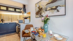 Una cocina moderna con comedor, que presenta una mesa de vidrio, una silla de cuero marrón y un jarrón con flores.