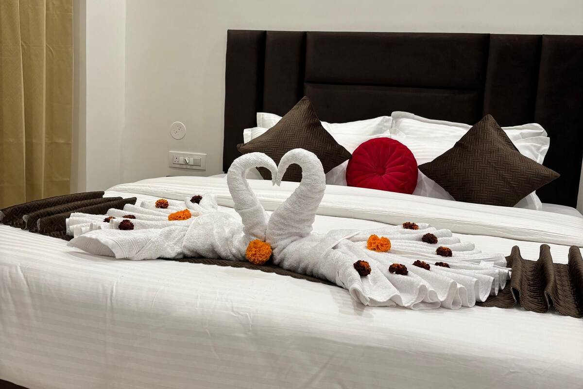 A neatly made bed with a swan towel arrangement and decorative pillows.
