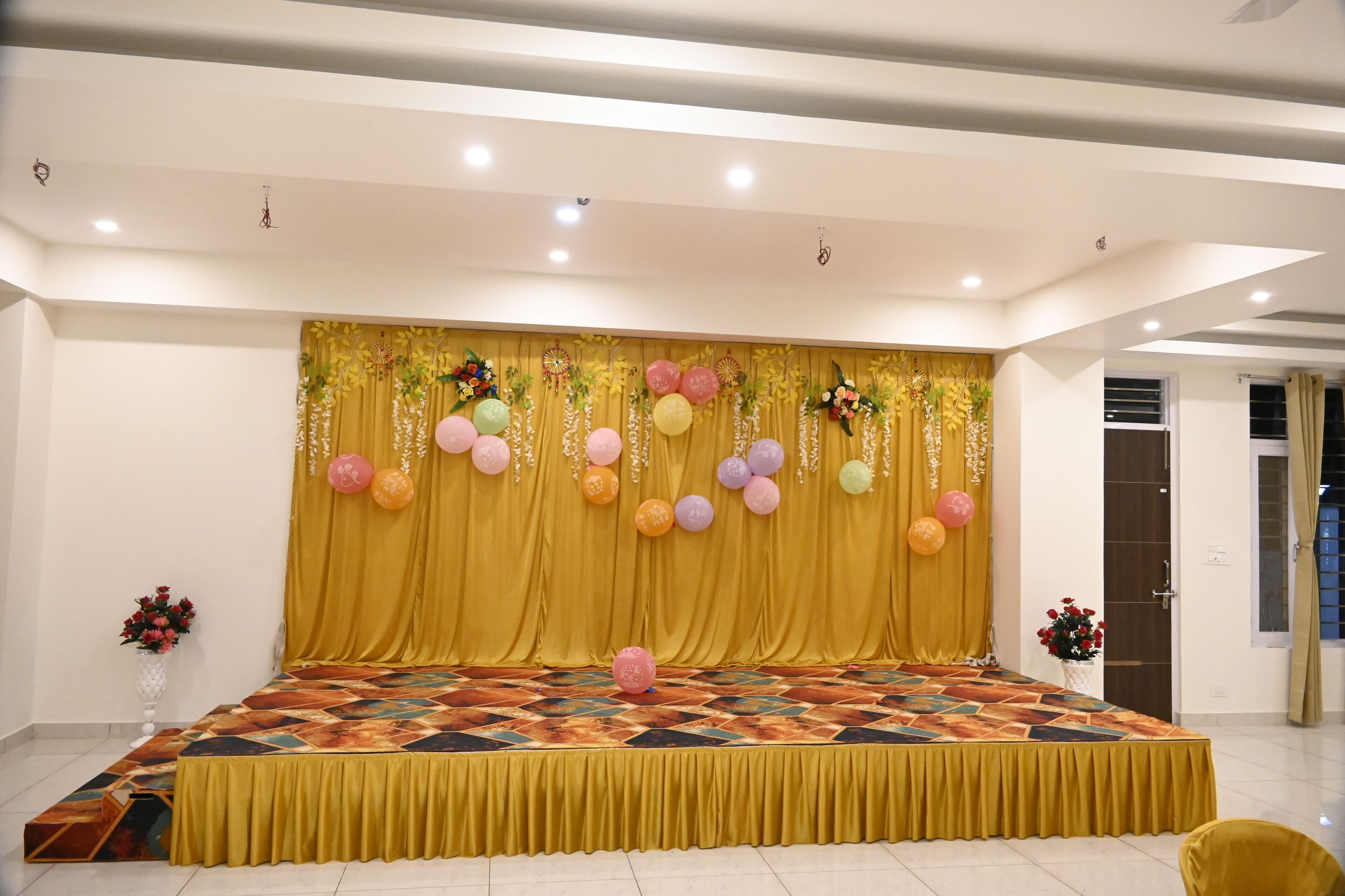 Un escenario con alfombra estampada, cortinas amarillas y globos.