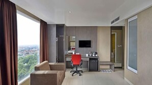 Ein Hotelzimmer mit Bett, Schreibtisch, Stuhl, Fernseher und Blick auf die Stadt.