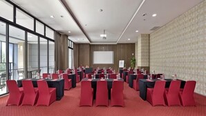 Ein Konferenzraum mit runden Tischen, roten Stühlen, einer Projektionsleinwand und einem großen Fenster.