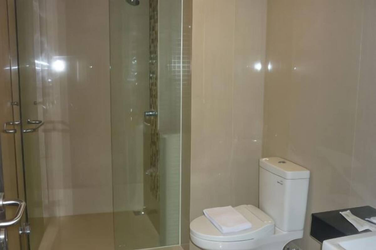 Egy modern fürőszoba üveg válaszfallal ellátott zuhanyzóval, WC-vel és mosdókagylóval.