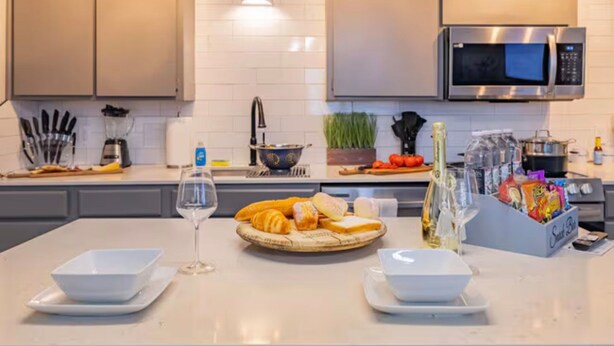 Une cuisine moderne avec des armoires blanches, un four à micro-ondes en acier inoxydable et une variété d’aliments disposés sur le comptoir.