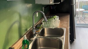 A kitchen with white cabinets, stainless steel sinks, and a green wall. - Cozy retreat In National Capital Region! (Gatineau)