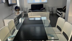 A modern conference room with a glass table, white chairs, a sofa, and a TV on the wall. - Cozy retreat In National Capital Region! (Gatineau)