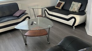 A modern living room with a glass coffee table, two sofas, and a small table with a remote control. - Cozy retreat In National Capital Region! (Gatineau)