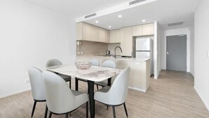 A modern kitchen with a marble countertop, white cabinetry, and a built-in oven. - The Residences at the Peninsula (Hope Island)