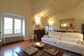 A living room with a white sofa, a dining table with chairs, a radiator, and a large mirror on the wall. - Il Vigneto, Verona, Pool, Wifi (Colognola Ai Colli)