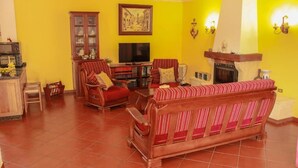 A living room with a red sofa, wooden cabinet, television, and fireplace.