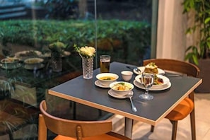 A dining table set with plates, bowls, and a glass of water, with chairs around it. - TUI BLUE The Haven Ipoh (Ipoh)