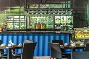 An indoor bar area with a blue counter, shelves with bottles, and a display case with food items. - TUI BLUE The Haven Ipoh (Ipoh)