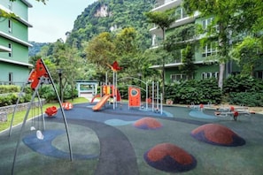 A playground with slides and climbing structures, surrounded by greenery and buildings. - TUI BLUE The Haven Ipoh (Ipoh)
