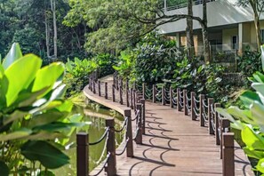 A wooden pathway with chain-link railings, surrounded by lush greenery and leading to a building. - TUI BLUE The Haven Ipoh (Ipoh)