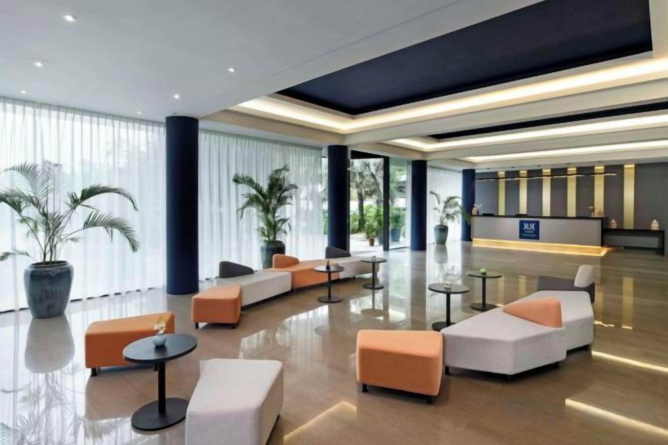 A modern lobby with seating areas, a reception desk, and large windows.