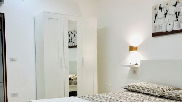 Un dormitorio con una cama grande, un armario y una lámpara fijada a la pared.