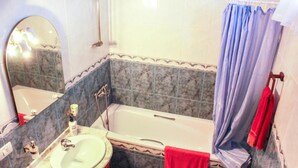 A bathroom with a bathtub, a sink, and a mirror.