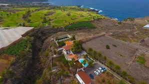 A coastal property with a swimming pool, a tennis court, and a view of the ocean.