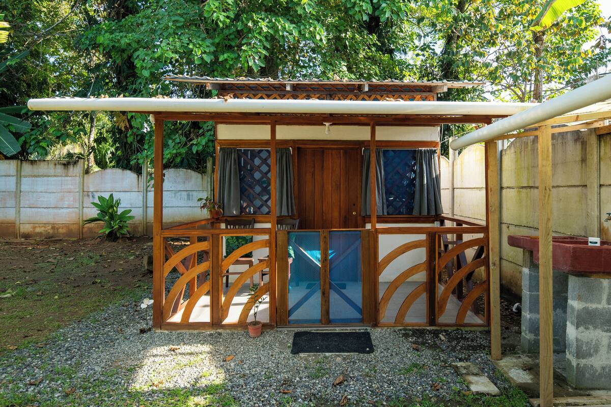 A small wooden structure with a sliding door, a small porch, and a potted plant.
